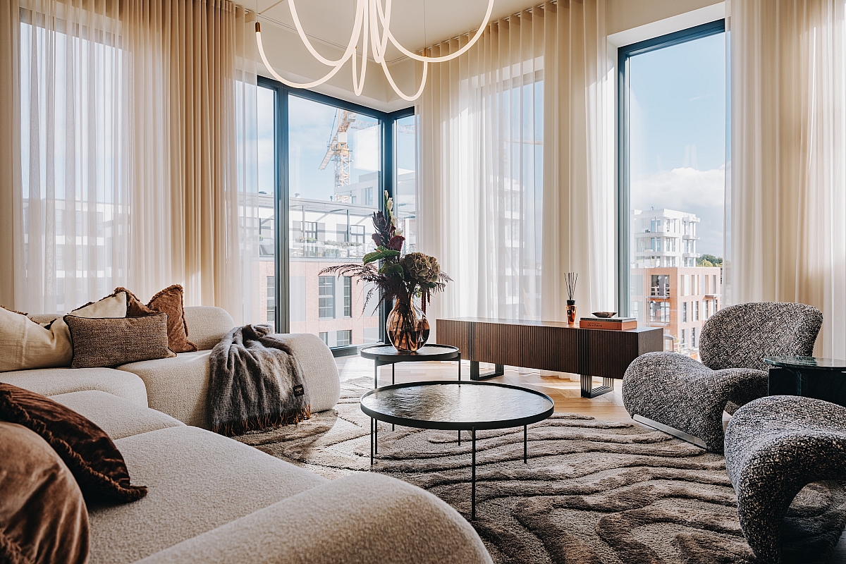 Avar, helge ja rahulik elutuba. Suured aknad toovad elutuppa rohkelt loomulikku valgust, mis liigub üle pehmete tekstuuride, toob esile tasakaaluka värvigamma ning laseb tekstuursetel detailidel mõjule pääseda. Foto: Volta Galerii Loftide näidiskorter, elutuba, sisekujundus Palazzo Interiors.