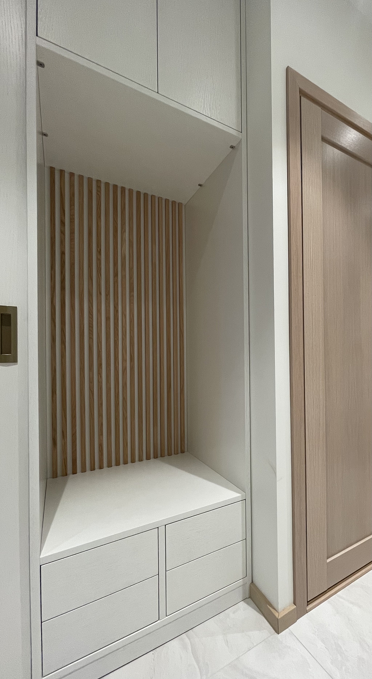 Foto: Tank Indoori väikese esiku lahendus – käändustega kapi kõrval asub nišš, kus on pink ja puitribisein 1